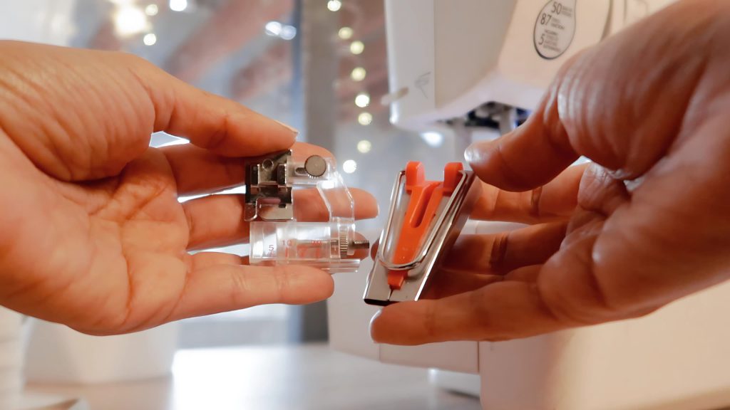 hands holding a red bias maker tool and a bias binder presser foot